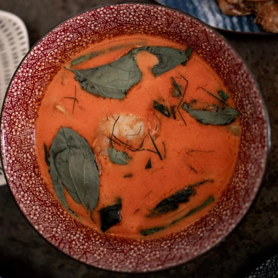 Curry rouge aux feuilles de basilic, dans un bol rouge, vu du dessus.